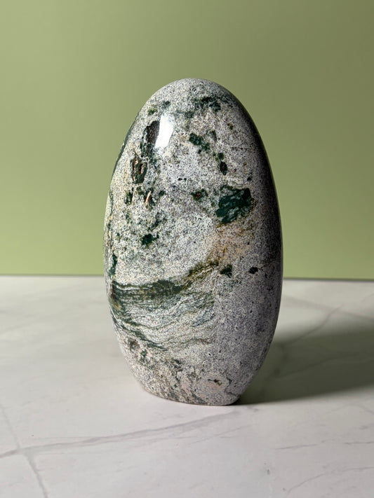 Polished stone with green and gray patterns on a light surface and green background