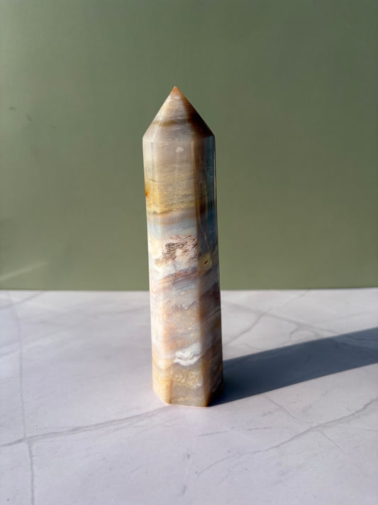 Polished sea jasper tower with soft bands of beige, cream, tan, and muted blue.