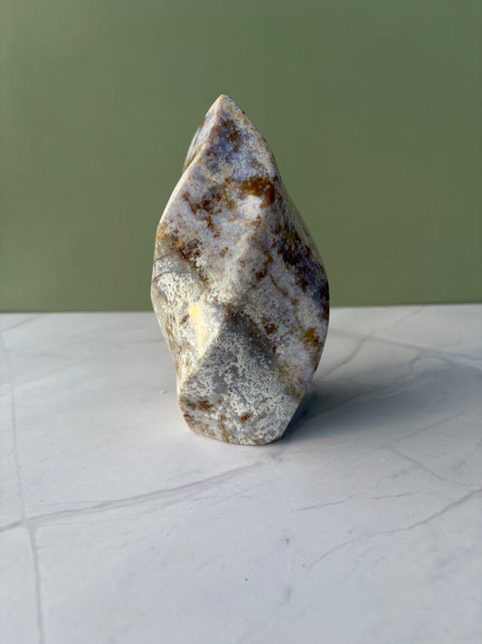 Sea jasper flame with soft gray, cream, and warm brown orbicular patterning on marble surface.